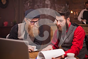 Two bearded collegues working together on a computer in a coffee shop