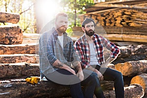 two bearded lumberjacks resting and sitting on logs