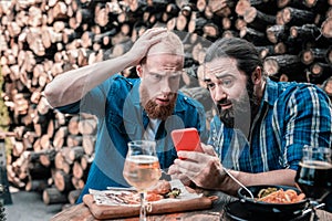 Two bearded men feeling shocked after checking score of the game