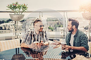 Two bearded men having conversation at outdoor cafe
