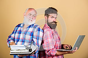 Two bearded men. Vintage typewriter. father and son. technology development and improvement. retro typewriter vs laptop