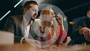 Two bearded men and young woman are talking make bets gambiling in a casino. Entertainment industry and luxury lifestyle