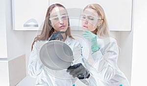 Two beauticians pose in a medical salon with a mirror in their hands. Rejuvenation concept
