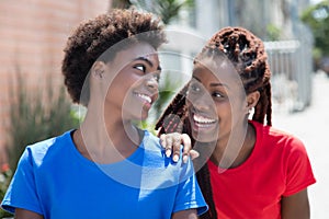 Two beautiful african american woman talking in city