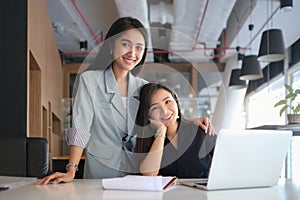 Two beautiful asian businesswoman working together in modern office and smiling to camera