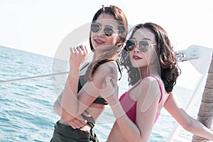 Two beautiful asian women wearing bikini and standing beside the sea
