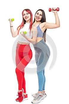 Two beautiful, athletic, slender and cheerful female friends are smiling and holding dumbbells in their hands. In full