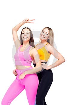 Two beautiful, athletic, slim and cheerful female friends are smiling. Lifestyle concept with sports and gym. Isolated