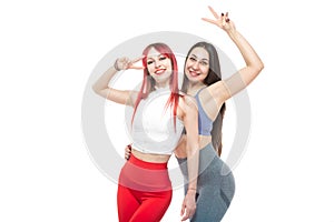 Two beautiful, athletic, slim and cheerful female friends are smiling. Lifestyle concept with sports and gym. Isolated