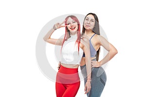 Two beautiful, athletic, slim and cheerful female friends are smiling. Lifestyle concept with sports and gym. Isolated