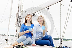 Two beautiful, attractive young girls drinking coffee on a yacht