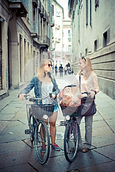 Two beautiful blonde women shopping on bike