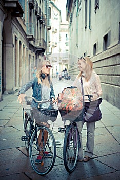 Two beautiful blonde women shopping on bike