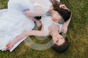 Two beautiful brides lying on the green field