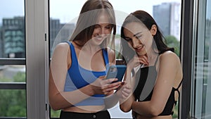 Two beautiful caucasian girls look at the screen of a mobile phone in a woman's hand. Girls talk and laugh, while