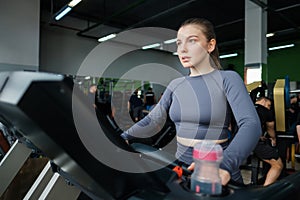 Two beautiful caucasian girls run on a treadmill in the gym.