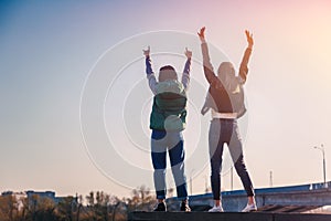 Two beautiful cool teenage girls 15-16 years old, best friends having fun, with their hands up