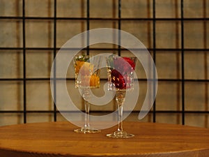 Two beautiful crystal wineglasses full of fruit ice cream. Colorful sorbet with decorative mint on a latticed background