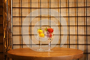 Two beautiful crystal wineglasses full of fruit ice cream. Colorful sorbet with decorative mint on a latticed background