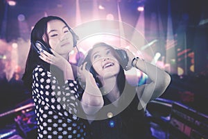 Two beautiful DJ plays music in the nightclub