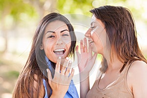 Two Beautiful Ethnic Twin Sisters Whispering Secrets Outdoors.