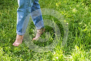 Two beautiful female feet walking on grass in sunny summer morning. Light step barefoot girl legs on soft spring lawn in