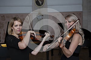 Two beautiful female violinists playing violin