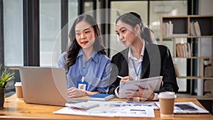 Two beautiful and focused young Asian businesswomen are sharing their project ideas