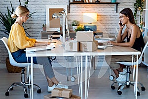 Two beautiful freelance business women seller working with computer while talking with smart phone in their startup small business