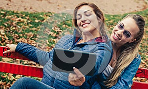 Two beautiful friends funny selfie on a tablet