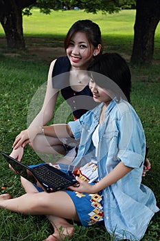 Two beautiful girl on a laptop computer outdoors