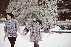 Two beautiful girlfriends hugging and smiling outdoors in winter. Two young female friends portrait closeup. Retouched, natural