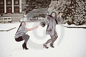 Two beautiful girlfriends hugging and smiling outdoors in winter. Two young female friends portrait closeup. Retouched, natural