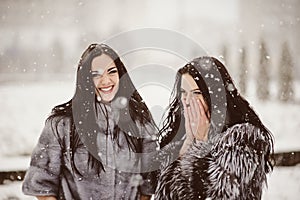 Two beautiful girlfriends hugging and smiling outdoors in winter. Two young female friends portrait closeup. Retouched, natural