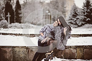 Two beautiful girlfriends hugging and smiling outdoors in winter. Two young female friends portrait closeup. Retouched, natural