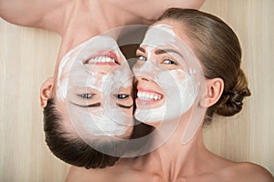 Two beautiful girls applying facial cream mask and
