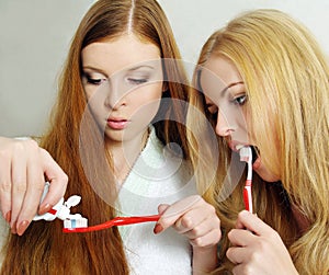 Two beautiful girls clean a teeth