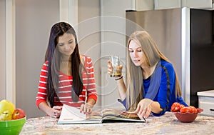 Two beautiful girls with cookbook in the kitchen