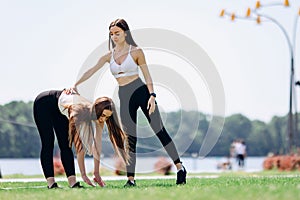 two beautiful girls do exercises outdoors in the park