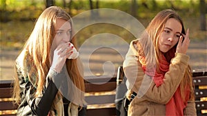 Two Beautiful Girls Eating Fast Food in the Park During Sunny Day in Autumn. Students Having Lunch Sitting on the Bench