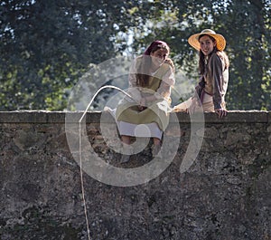 Two beautiful girls fishing from a bridge in a medieval event `Viagem Medieval em Terra de Santa Maria`, Santa Maria da Feira. photo