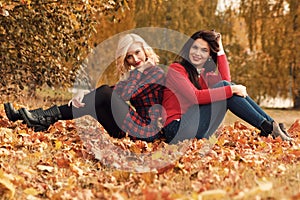 Two beautiful girls friends having fun in autumn park