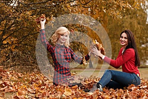 Two beautiful girls friends having fun in autumn park