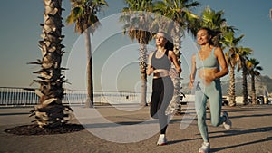 Two beautiful girls jogging at sunset or sunrise on beach. Young caucasian women running together. Brunette and blonde