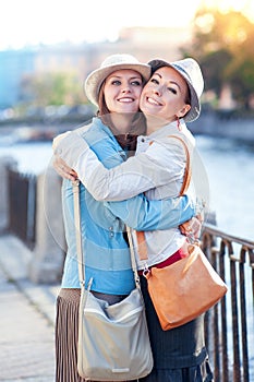 Two beautiful girls laughing and hug in the city