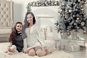 Two beautiful girls, mother and daughter siting on a floor in Ch