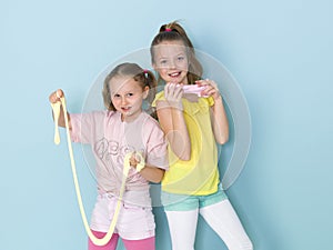 Two beautiful girls playing with homemade slime and having a lot of fun in front of blue background