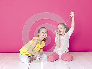 Two beautiful girls playing with homemade slime and having a lot of fun in front of pink background