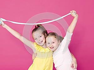 Two beautiful girls playing with homemade slime and having a lot of fun in front of pink background