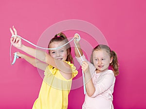 Two beautiful girls playing with homemade slime and having a lot of fun in front of pink background